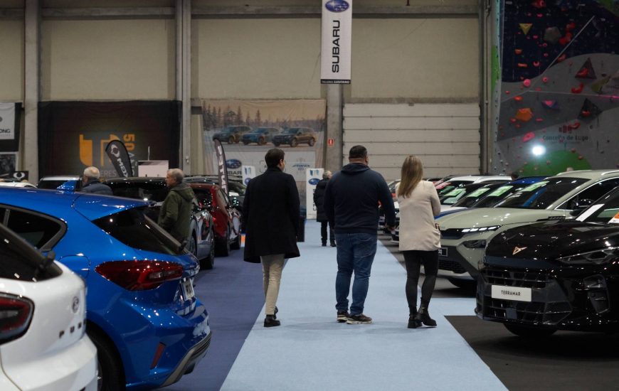 Tres personas pasean entre los coches del salón del automóvil lugo 2026
